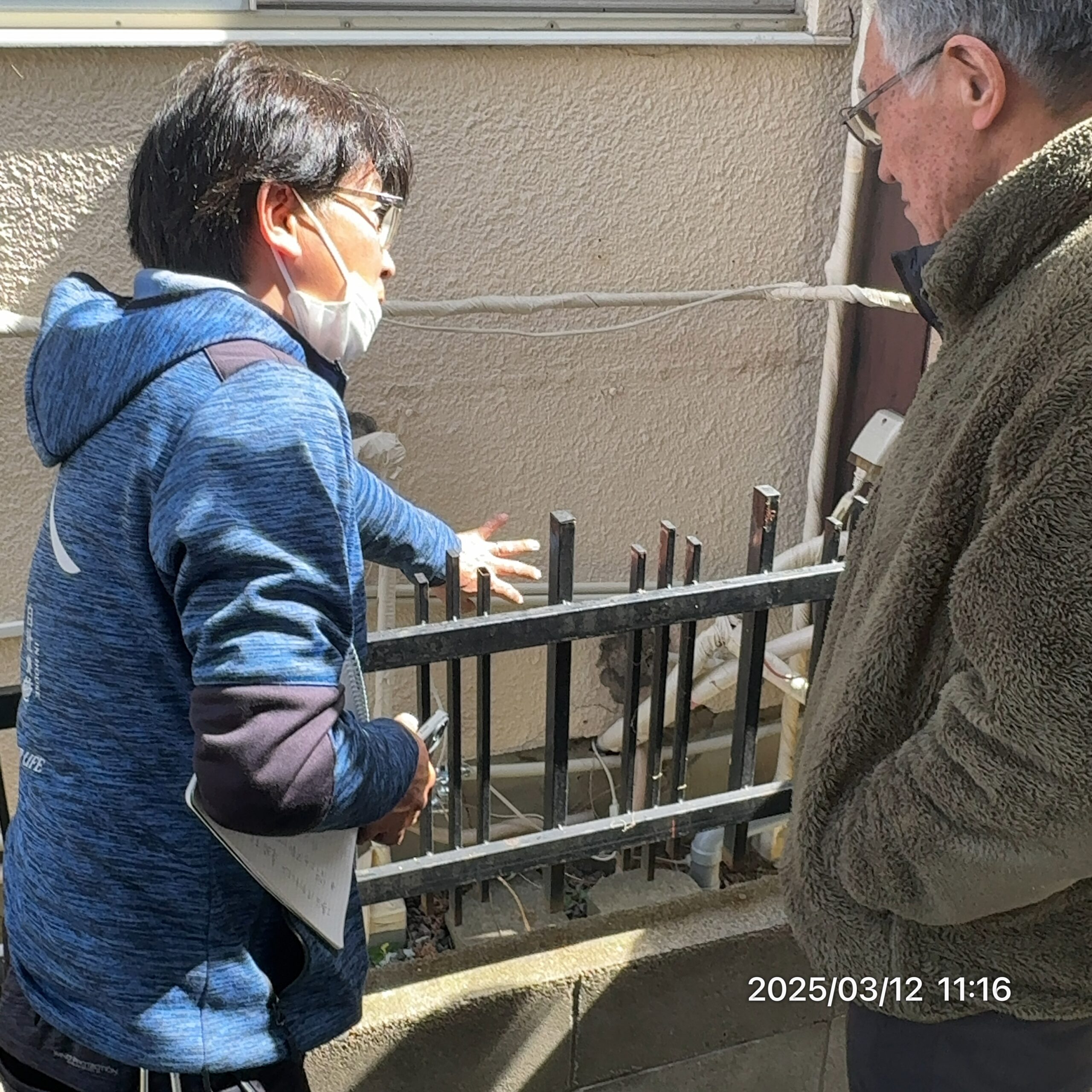 お客様に外壁の状態を説明する事業部長・小野