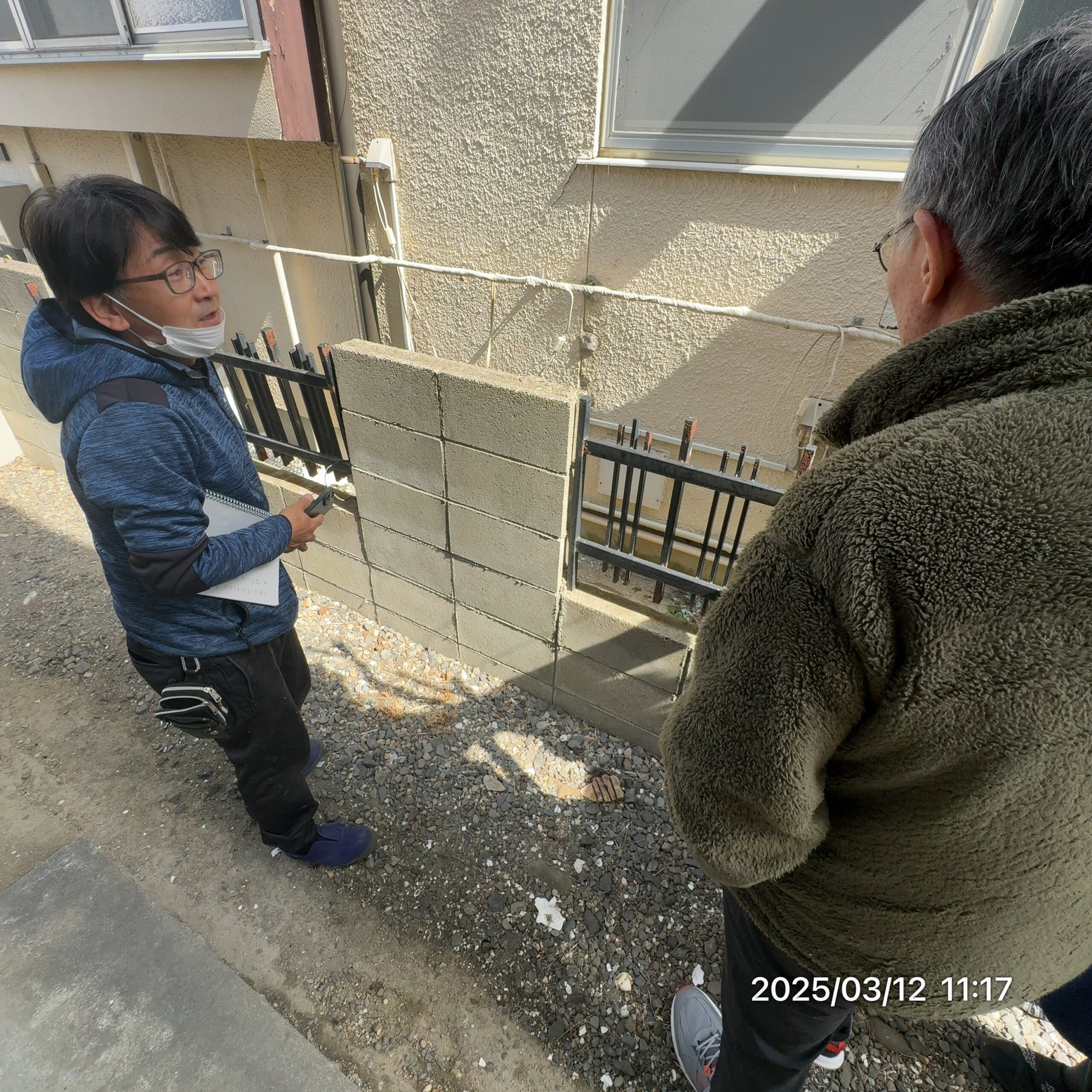 外壁の劣化箇所を指して説明する小野